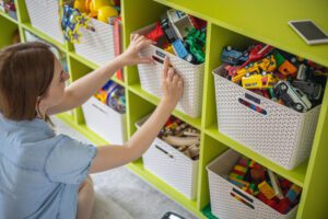picture of a mom organizing a child's bedroom by labeling bins for storage